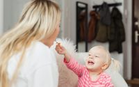 A heartwarming moment between a mother and her smiling child sharing a snack indoors.